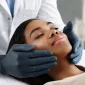 closeup beautician hands touching young female patient face 85x85